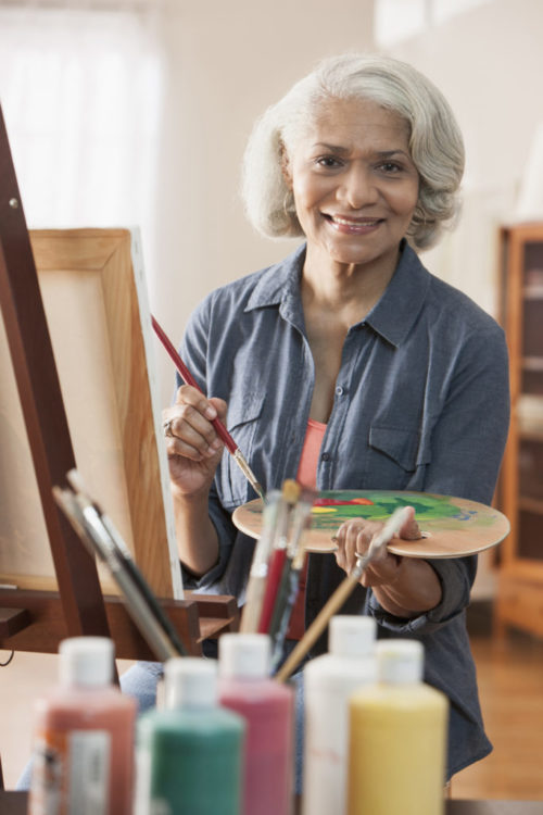 Woman painting a picture at an easel. 